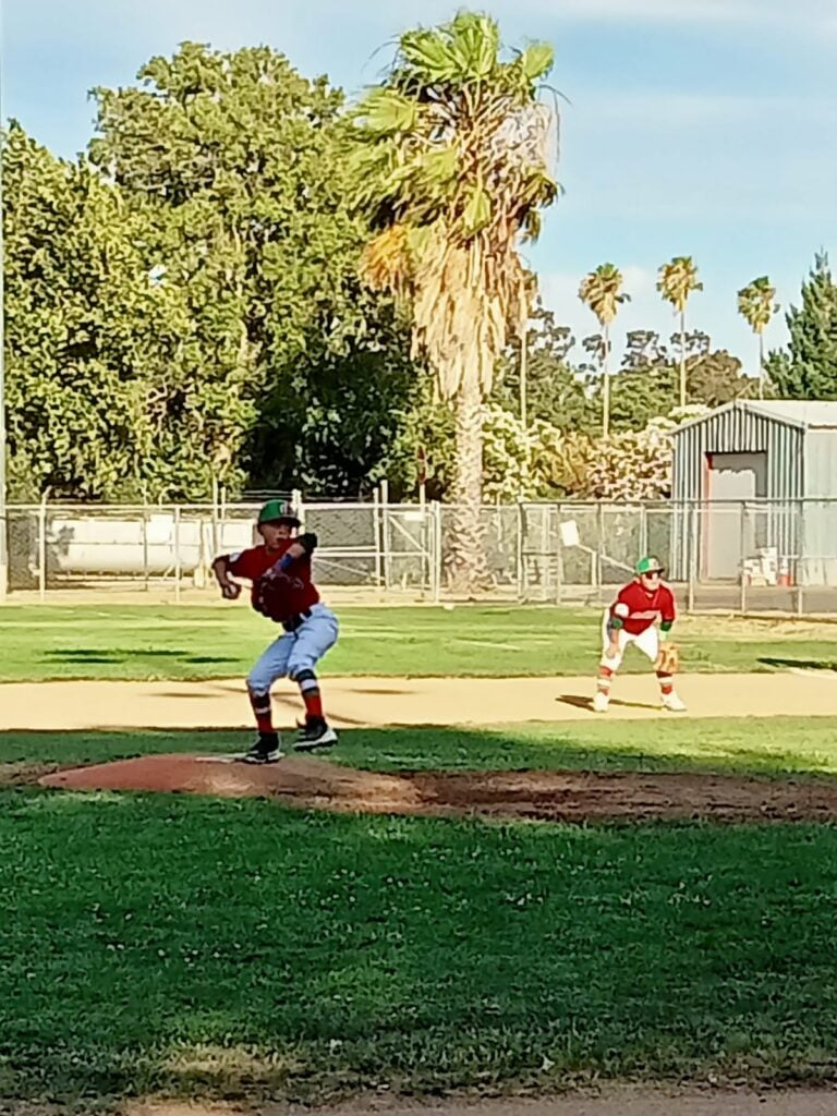 Un niño en la lomita de una cancha de beisbol y otro al fondo