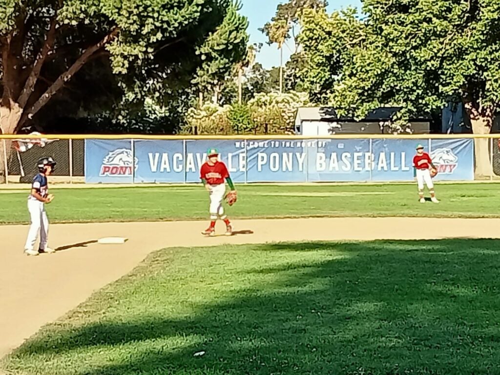 3 niños en una cancha de beisbol