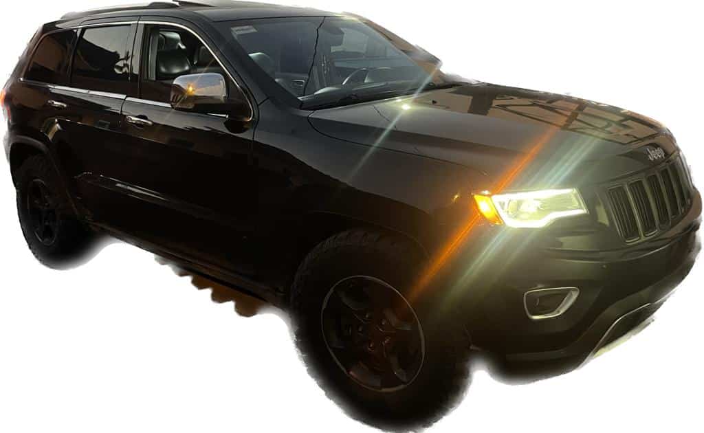 Una camioneta color negro con los focos encendidos