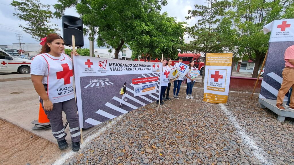 Personas con carteles en las manos y podium con el logotipo de la Cruz Roja