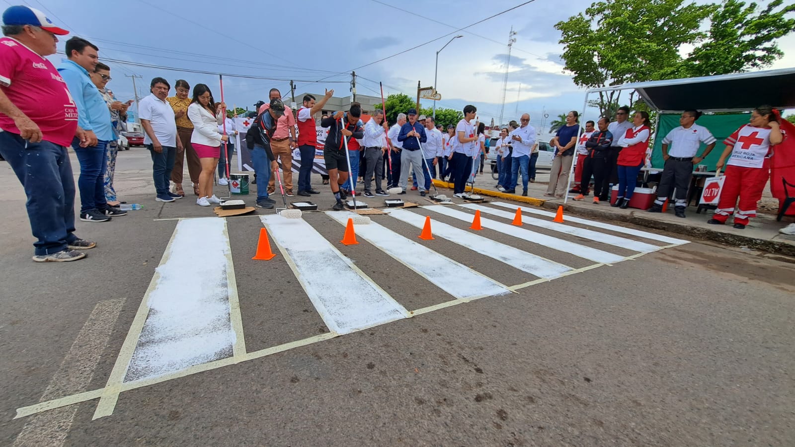 Calle pintada de rayas blancas, personas, conos y rodillos para pintar