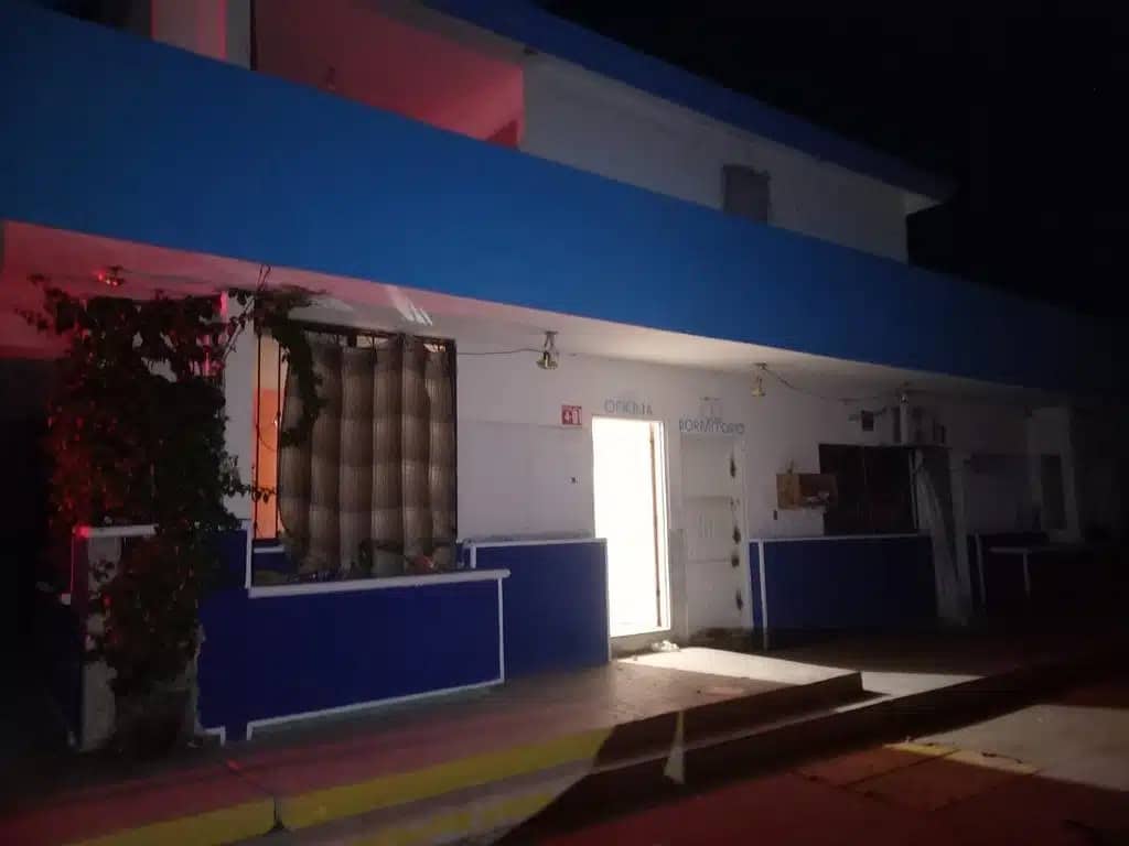Fachada de una casa, luz prendida, banqueta y ramas