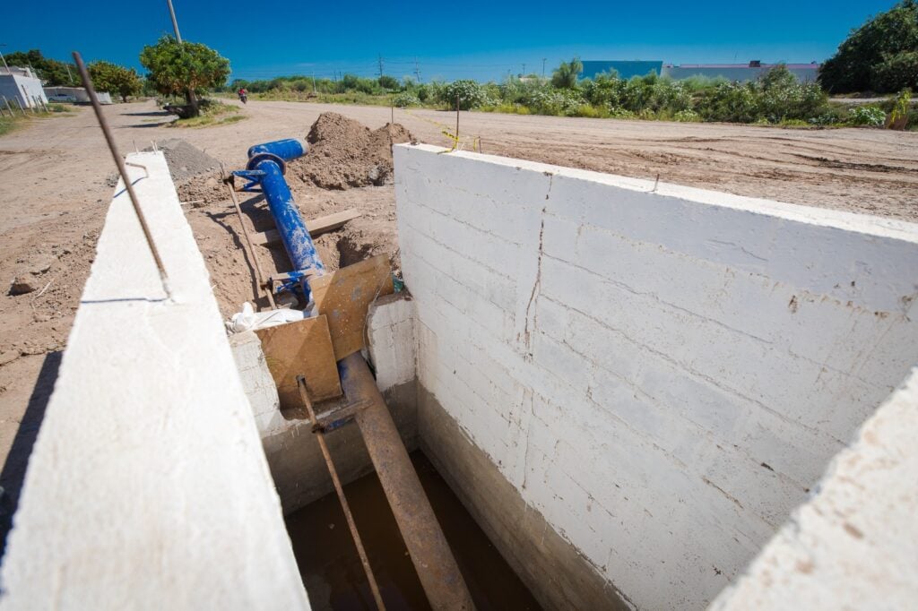 Paredes tipo barda de una estructura, tubos, tierra y árboles