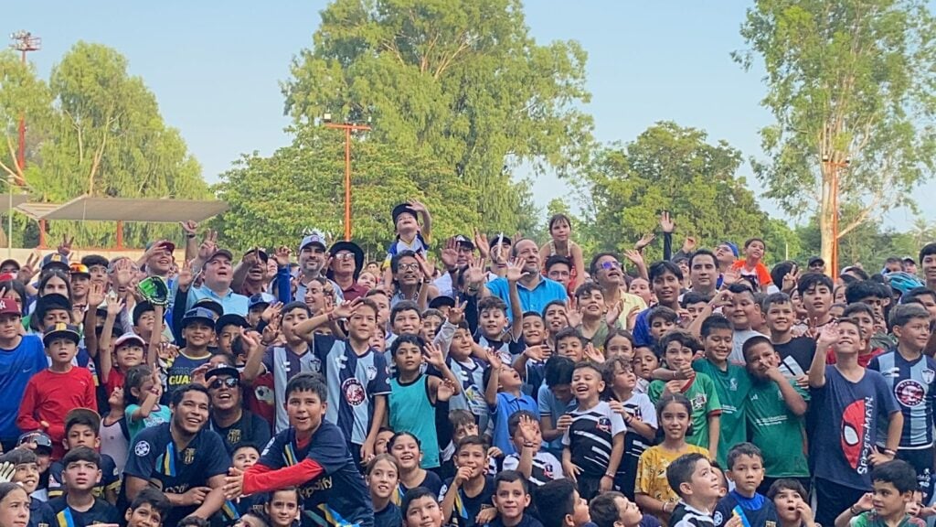 Niños saludando y sonriendo para una foto y árboles al fondo