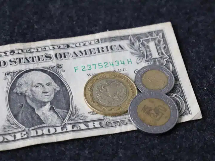 Un billete estadounidense con monedas mexicanas arriba de él