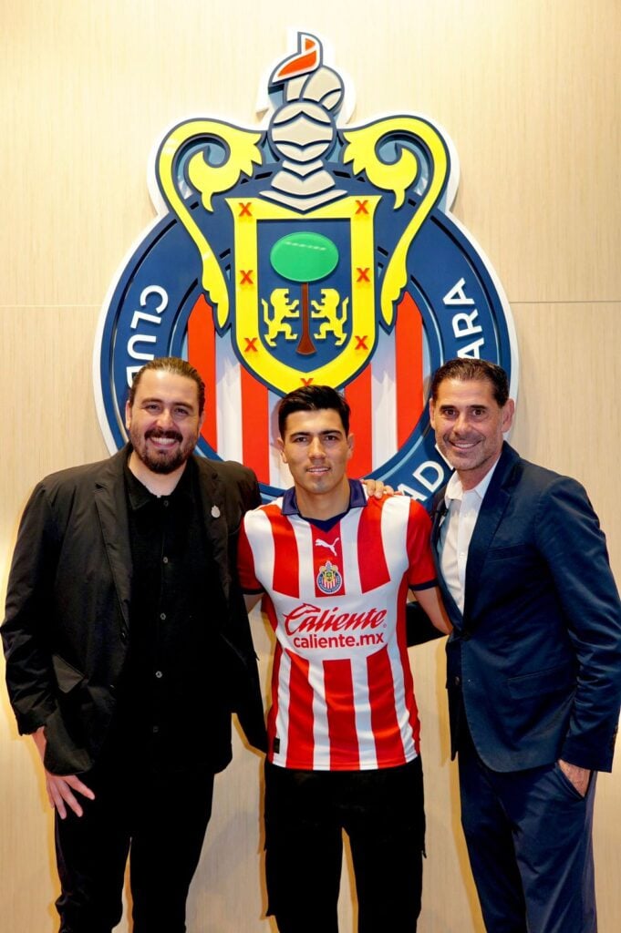 Tres personas y atrás el logo del equipo de Chivas