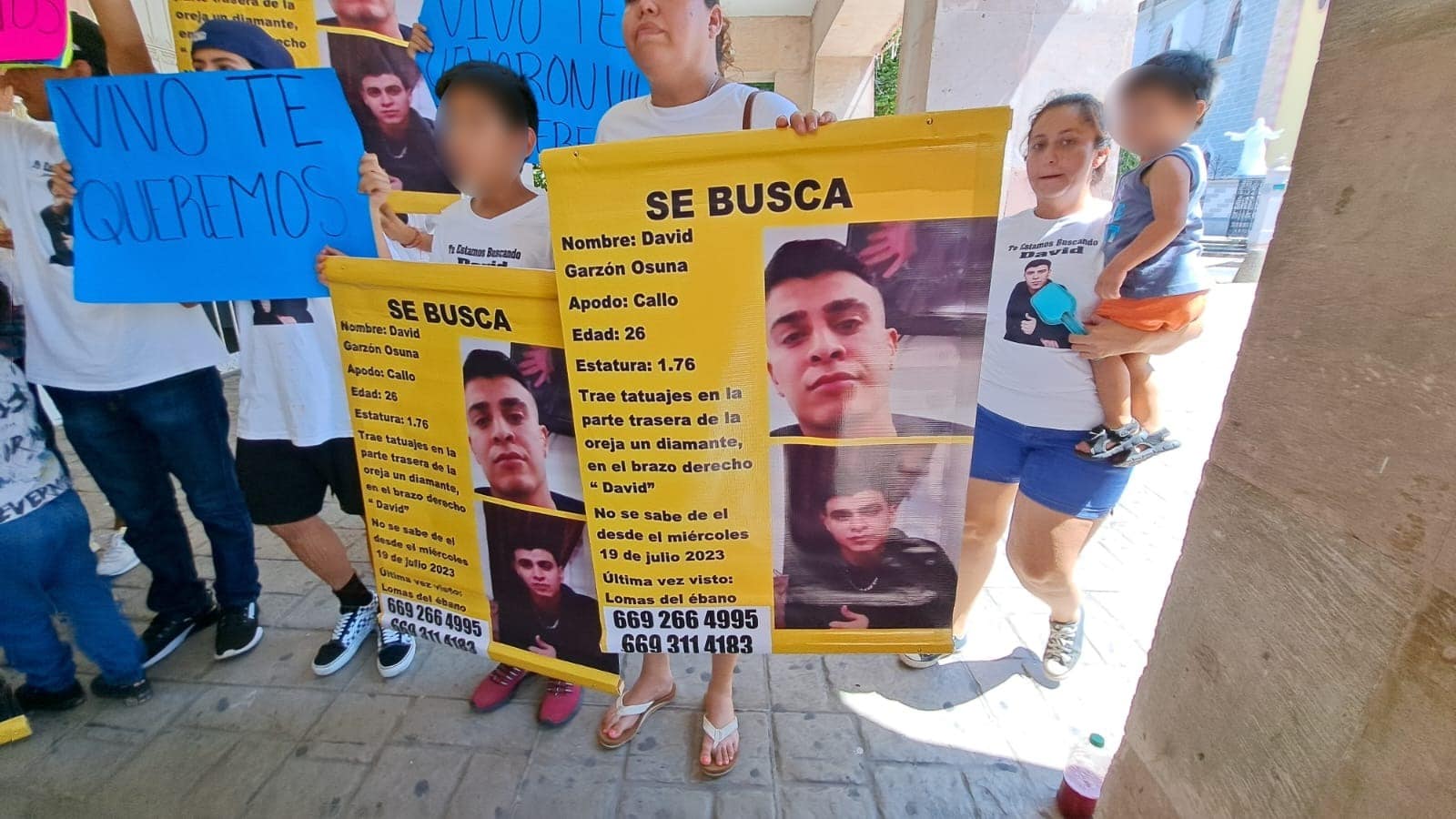 Personas con pancartas, con fotografías y letras