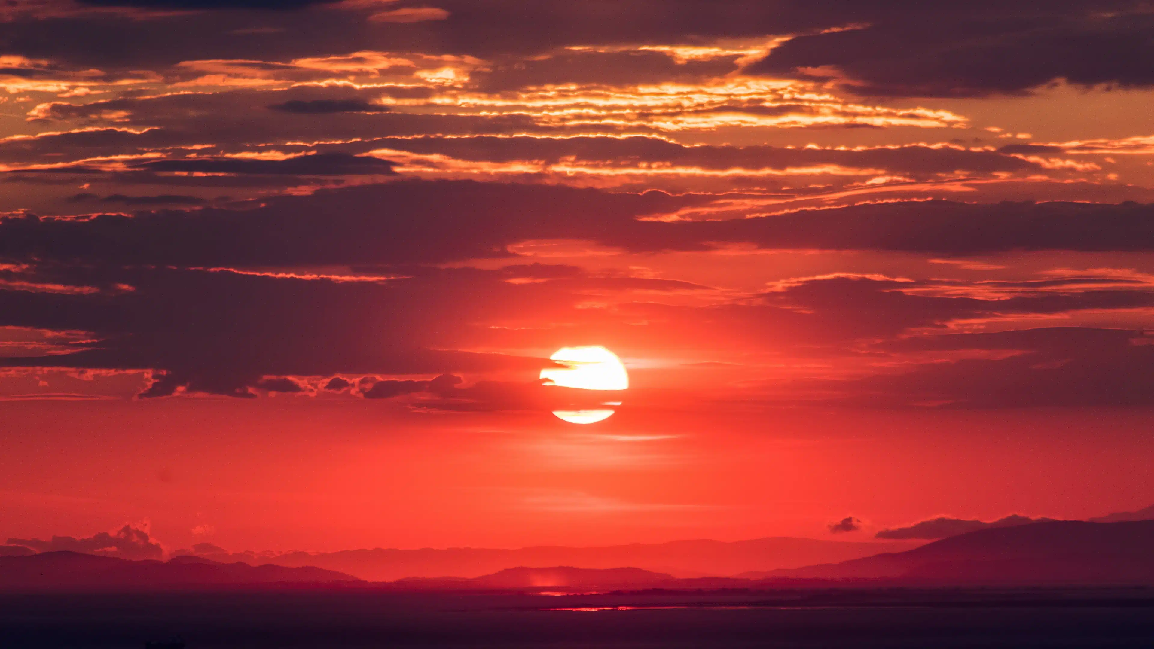 Cielo rojo con nubes y el sol