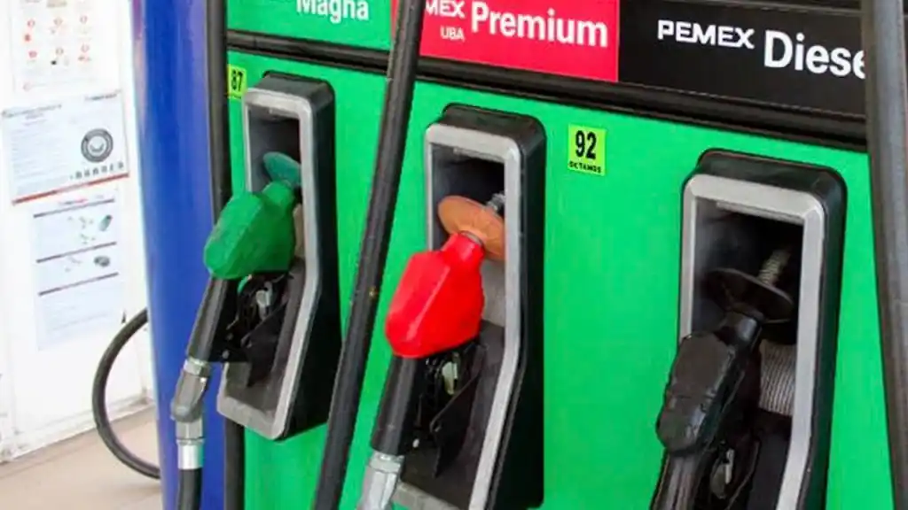 Bombilla de una estación de gasolina y 3 dispensadores de combustibles uno de color verde, otro rojo y otro negro