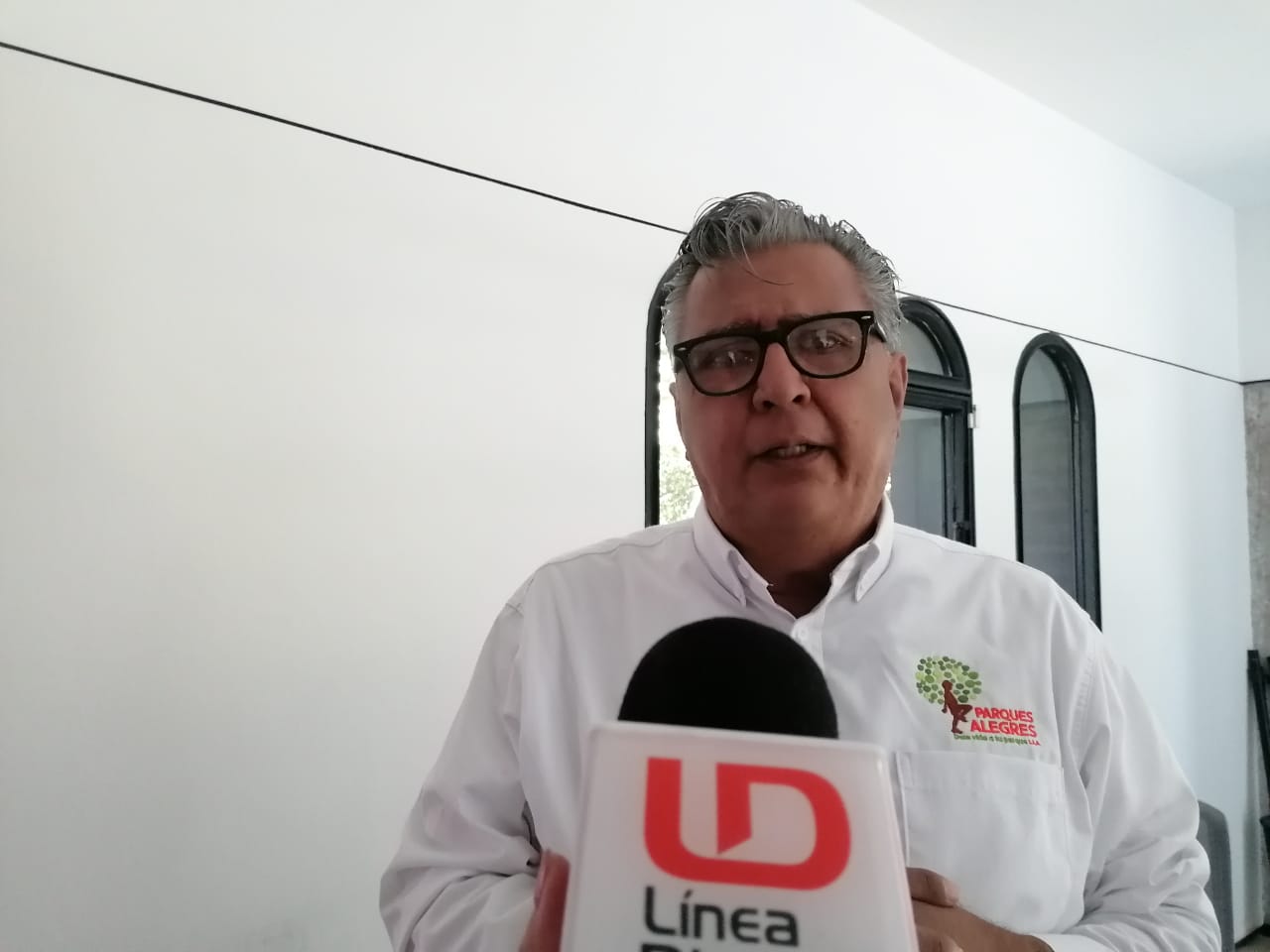 Una persona con lentes hablando y un micrófono de LD