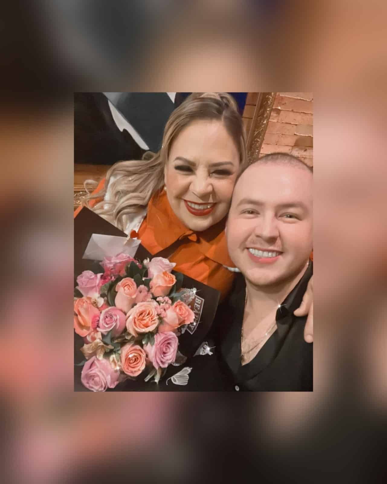Una señora con flores y un hombre ambos sonriendo