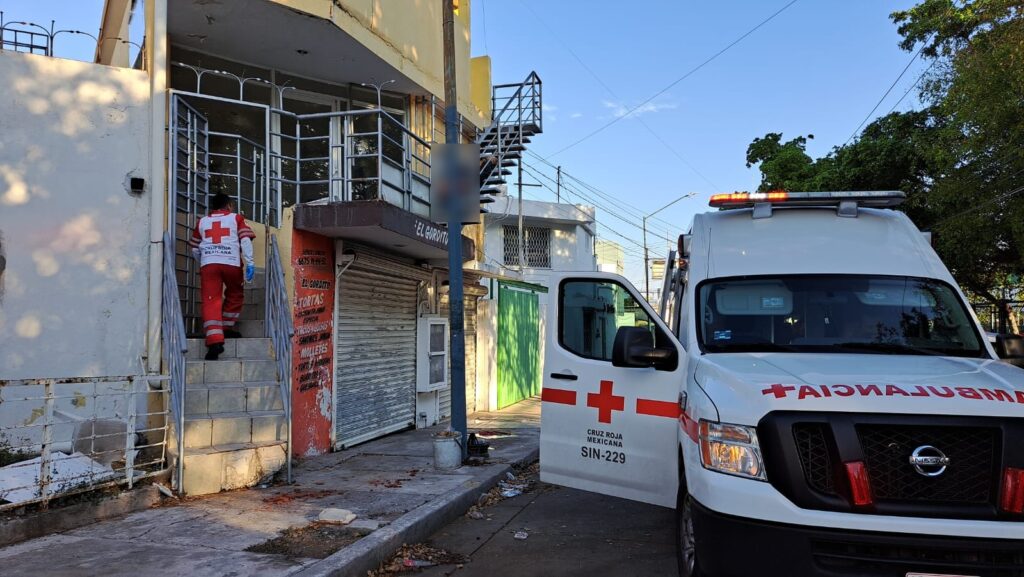 Una persona subiendo unas escaleras, un poste, una casa de 2 pisos y una ambulancia con la puerta abierta