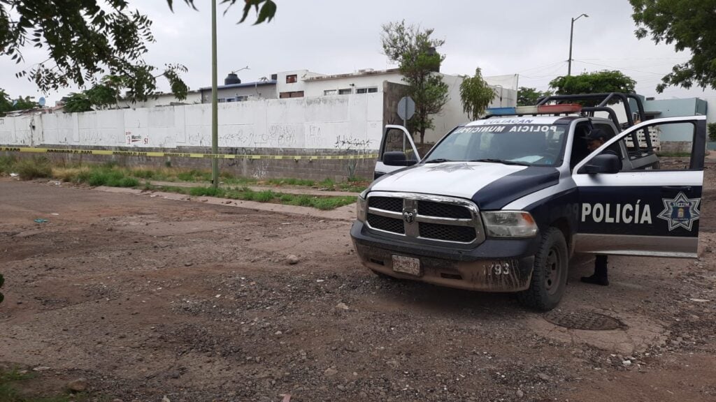 Una camioneta de la policía Municipal de Culiacán, árboles, calle y casas