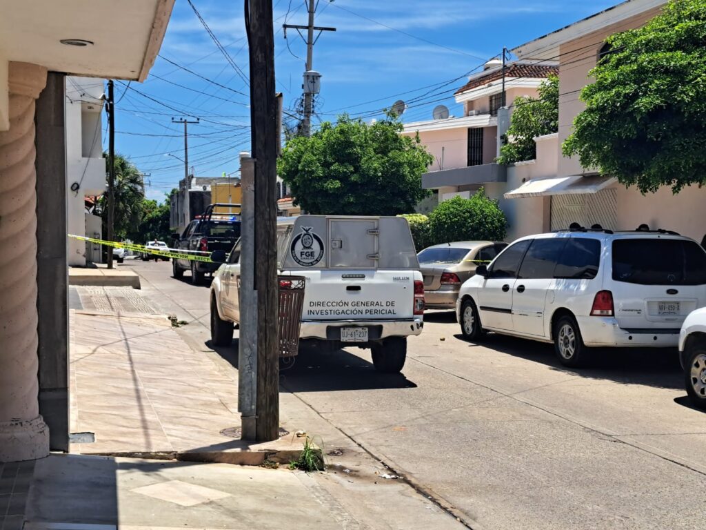Vista de atrás de la patrulla de la Dirección General de Investigación Pericial de la Fiscalía General de Justicia del Estado de Sinaloa afuera de un domicilio donde fue asesinado y municipal joven en Culiacán