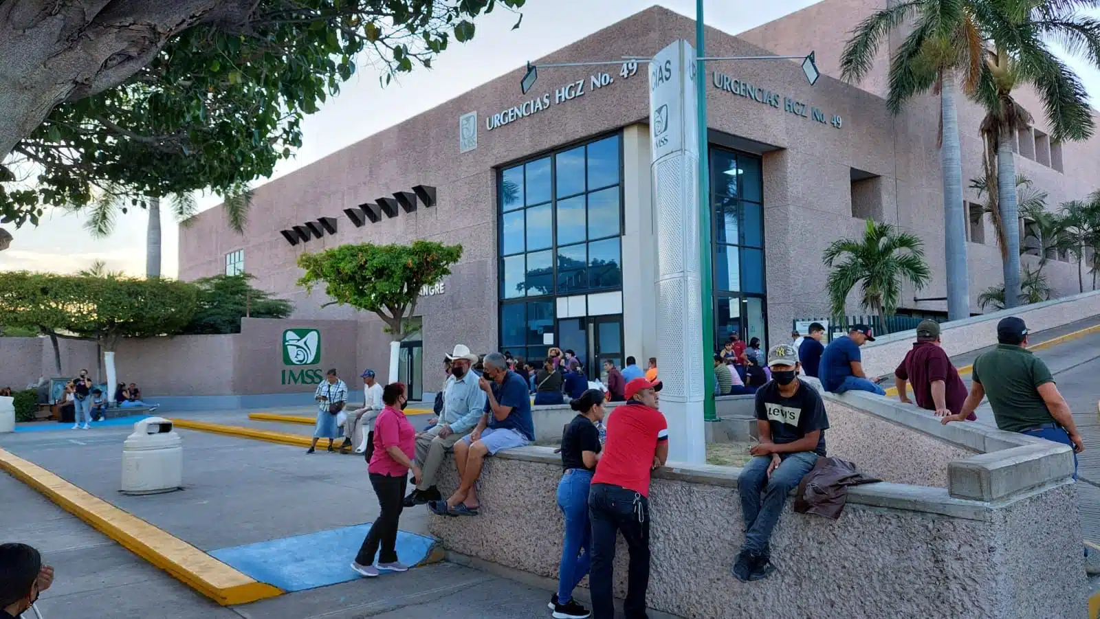 Personas sentadas y paradas afuera de las instalaciones del hospital IMSS Los Mochis