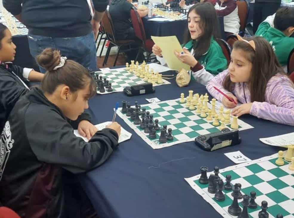 Niñas frente a un tablero de ajedrez; están jugando
