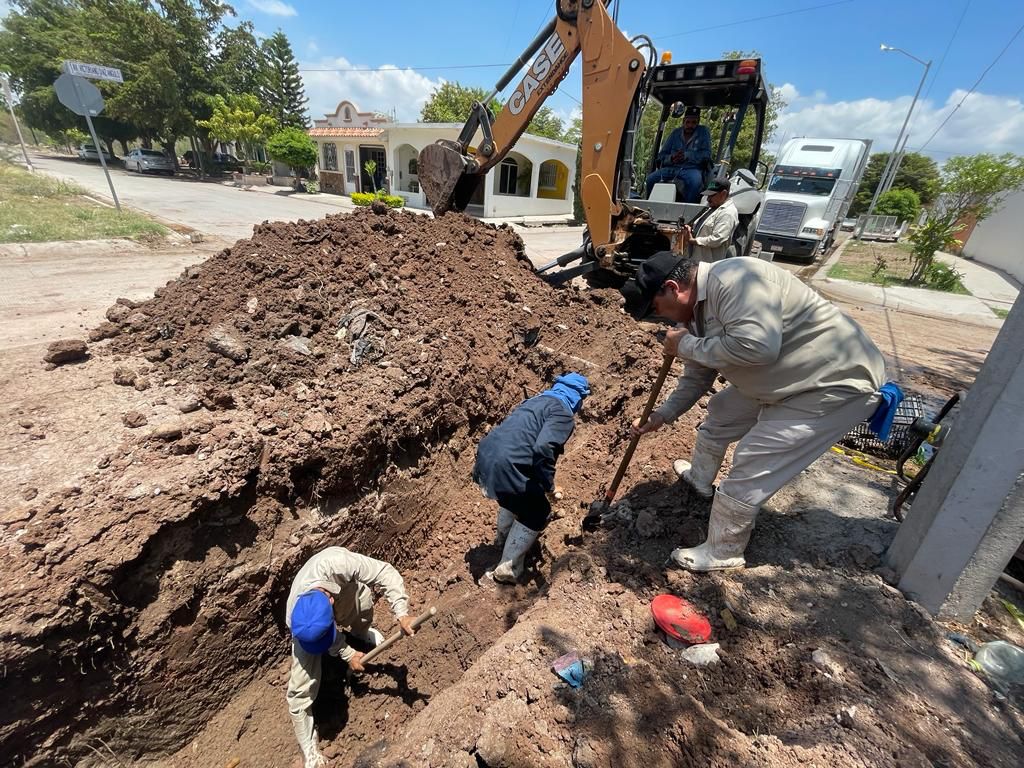 Tierra, una retroexcavadora, calle, casas y un tráiler al fondo