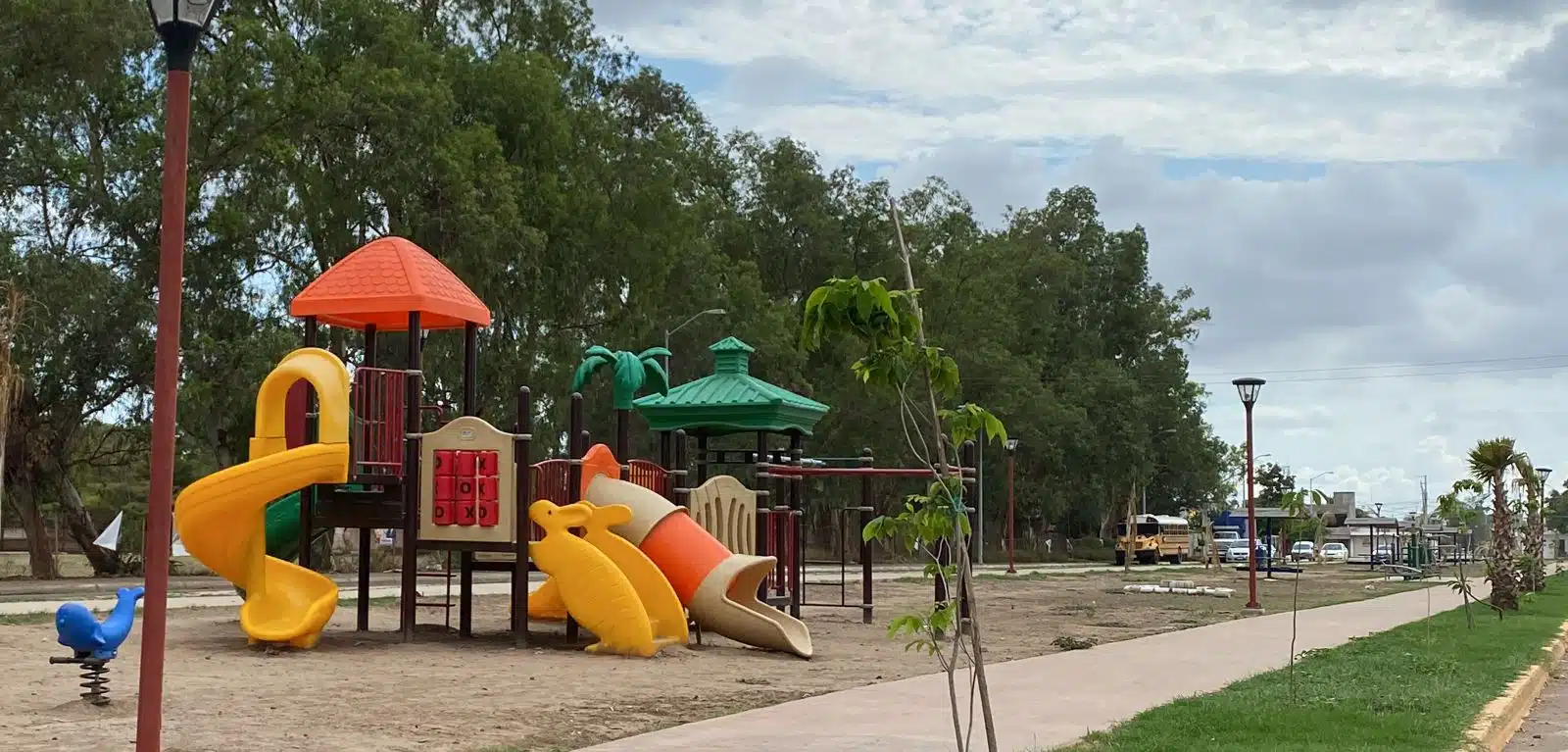 Juegos, parque lineal, árboles, césped y banqueta