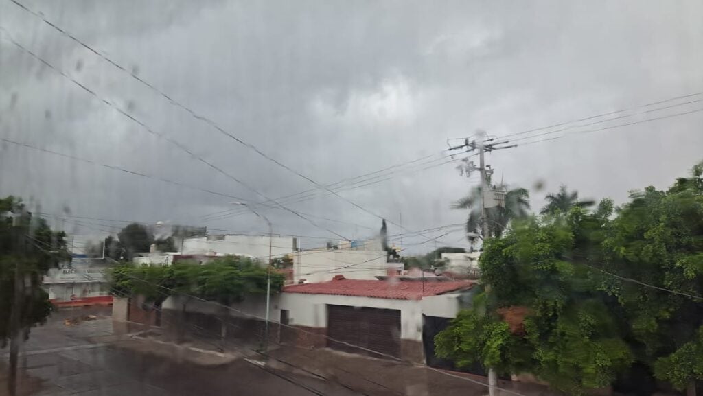 Cielo nublado, casas, árboles, poste y cables