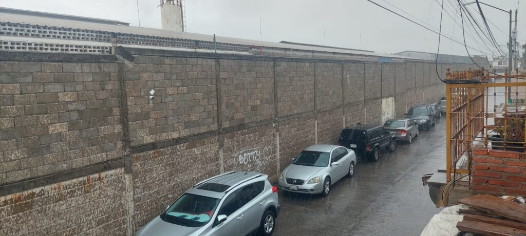 Carros, llovizna leve y pared de una construcción