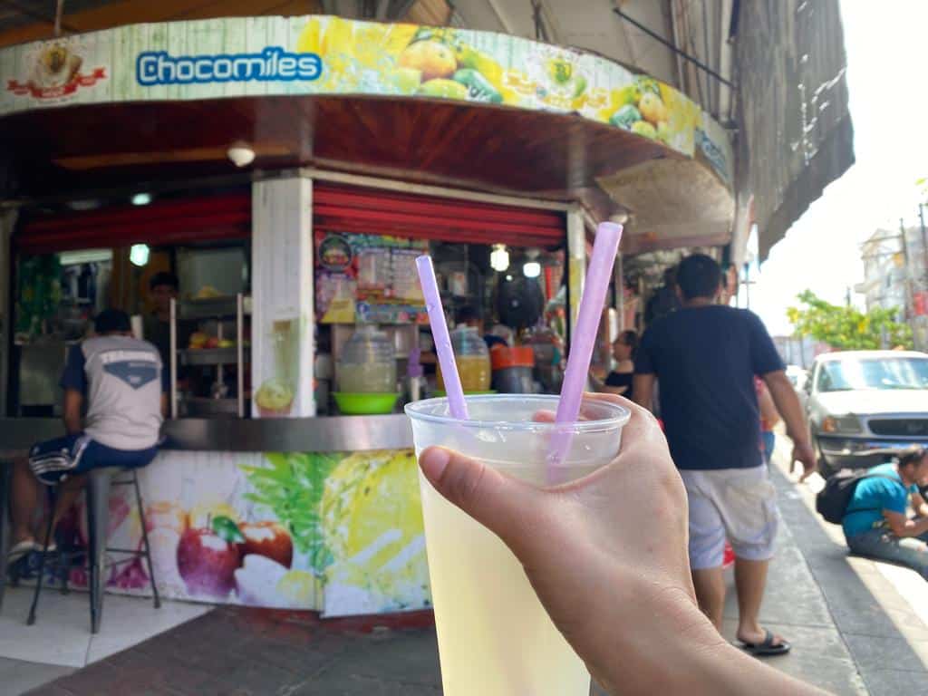 Mano sosteniendo vaso con agua fresca sabor limón