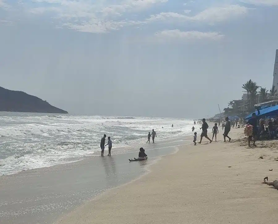 Personas en la orilla de la playa y en el mar