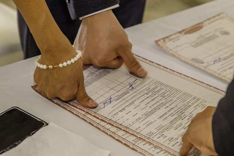 Pareja poniendo su huella en acta de matrimonio