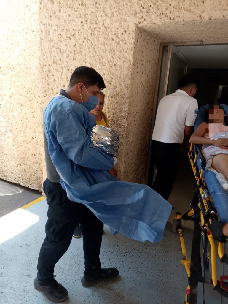 Paramédicos entrando al hospital con bebé y mujer atendida en parto