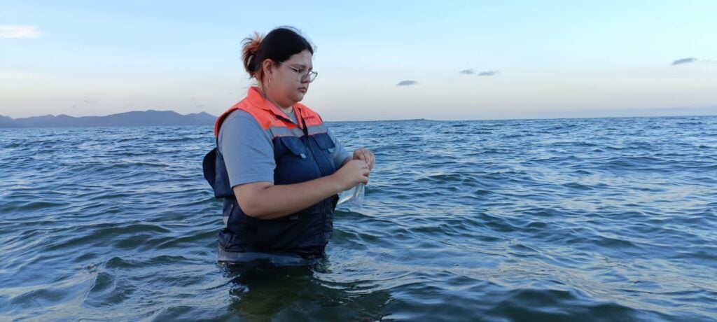 Agua de mar y una persona con lentes de lado adentro y una muestra de agua