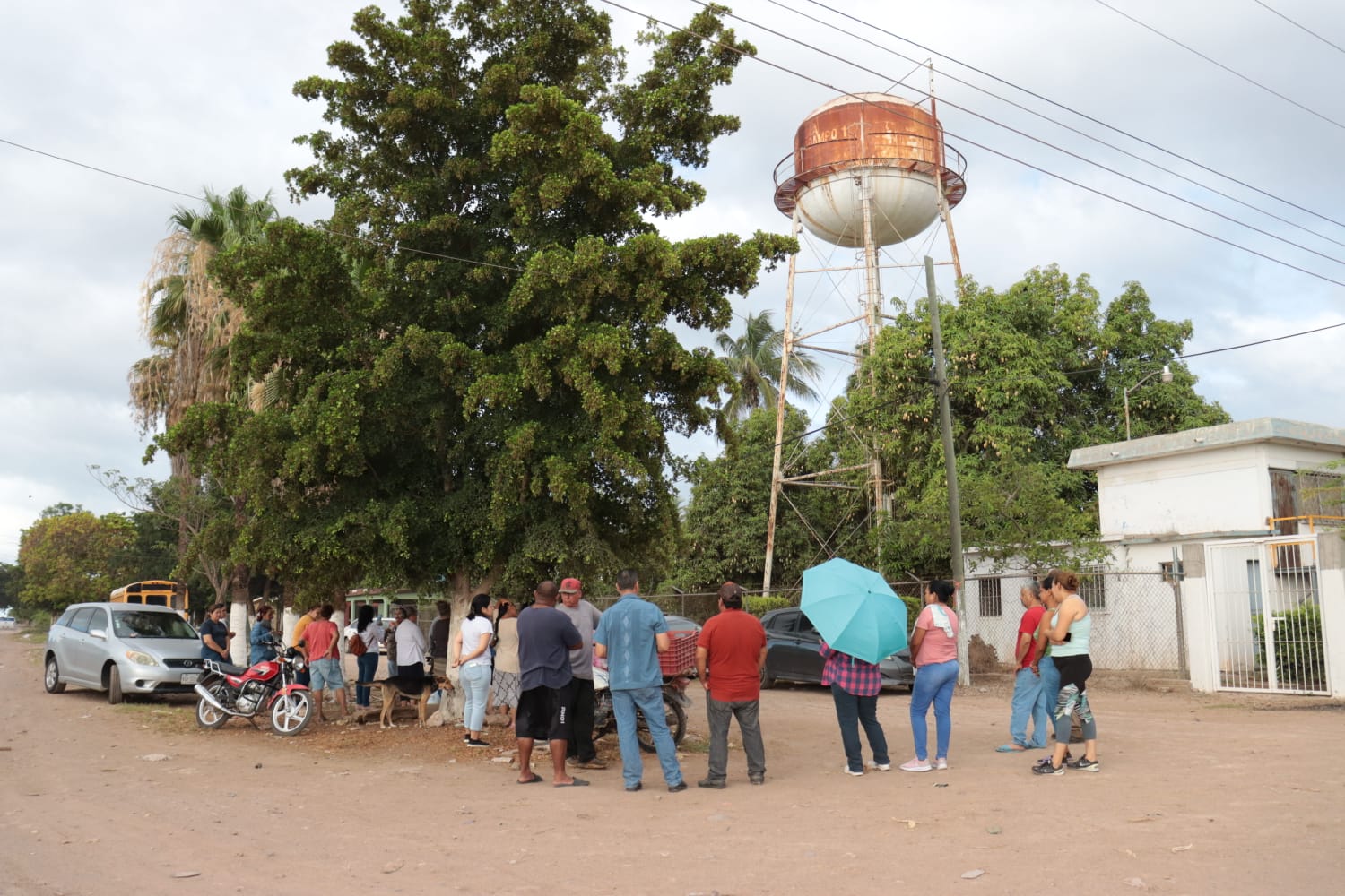 Un tanque, palmeras, nubes en el cielo, palmeras, árboles y personas paradas en la calle