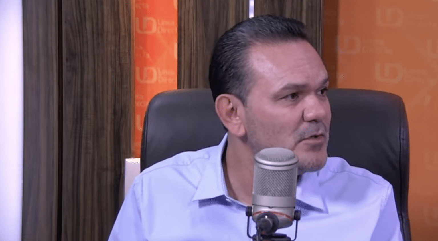 Una persona sentada hablando frente a un micrófono de radio