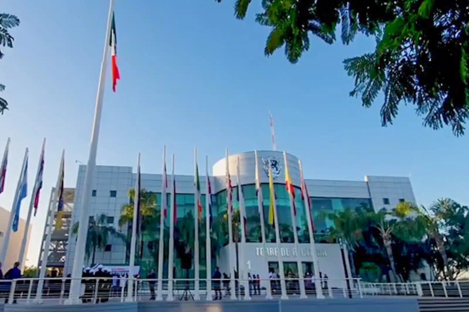 Edificio de la UAS, banderas una de ellas de México, árboles y palmeras