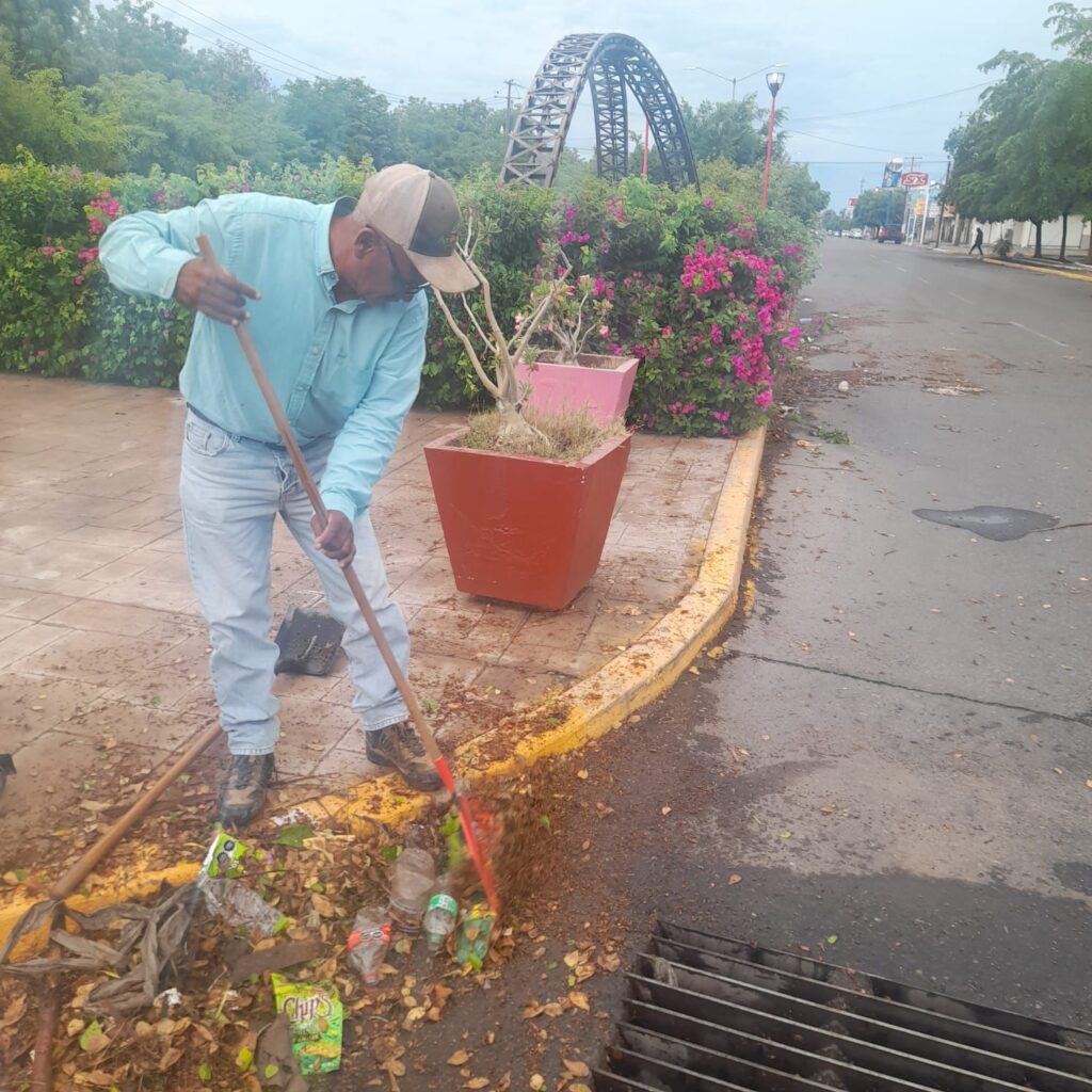 Un hombre limpia la basura acumulada en rejillas de drenaje pluvial
