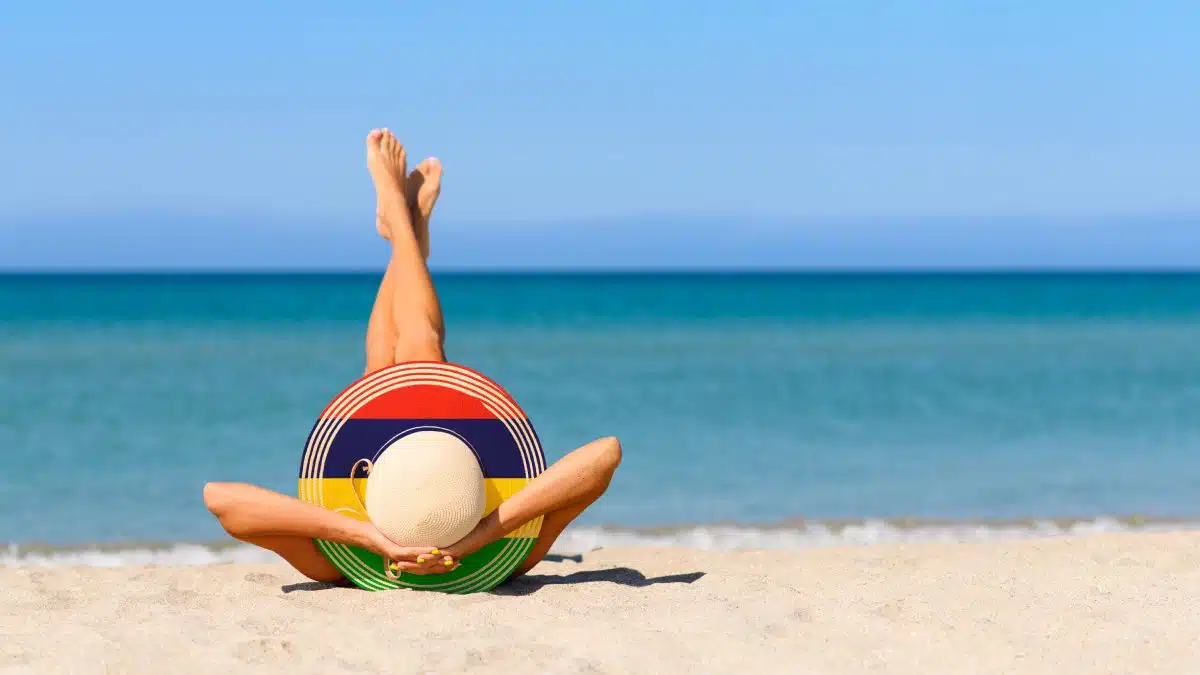 Una persona con un sombrero tomando el sol en la playa, arena y agua