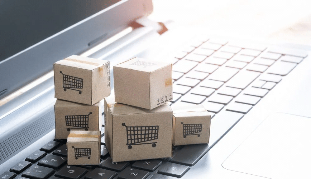 Cajitas de cartón con un carrito de supermercado dibujado encima del escritorio de una computadora
