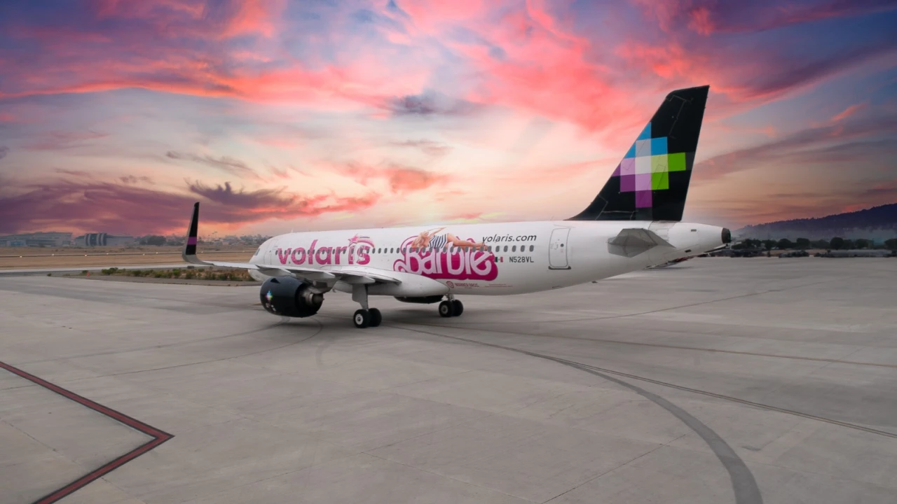 Un avión en la pista de aterrizaje con letras y logo de Volaris y Barbie