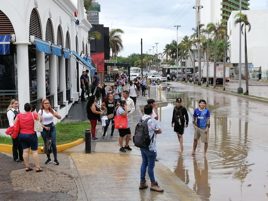 Calle inundada de agua y gente caminando sobre una banqueta