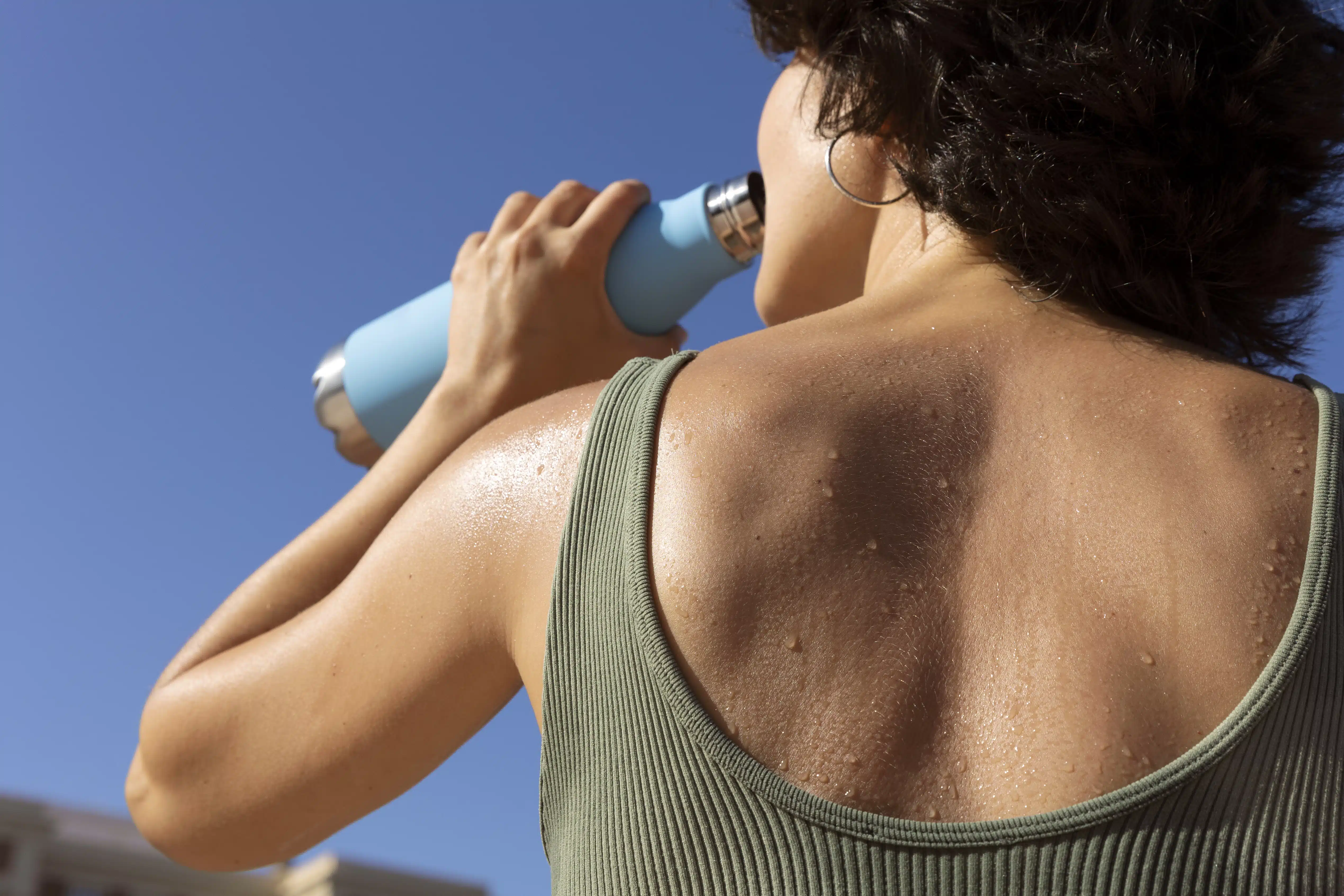 Mujer toma agua después de hacer ejercicio bajo el sol