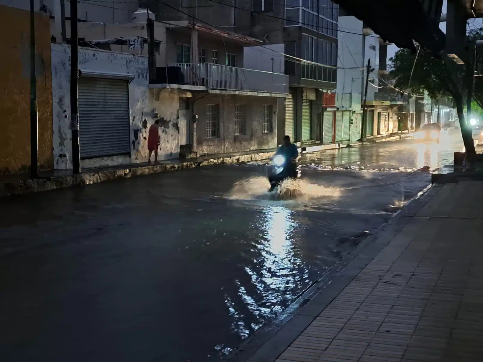 Moto conduciendo por una calle inundada entre los apagones