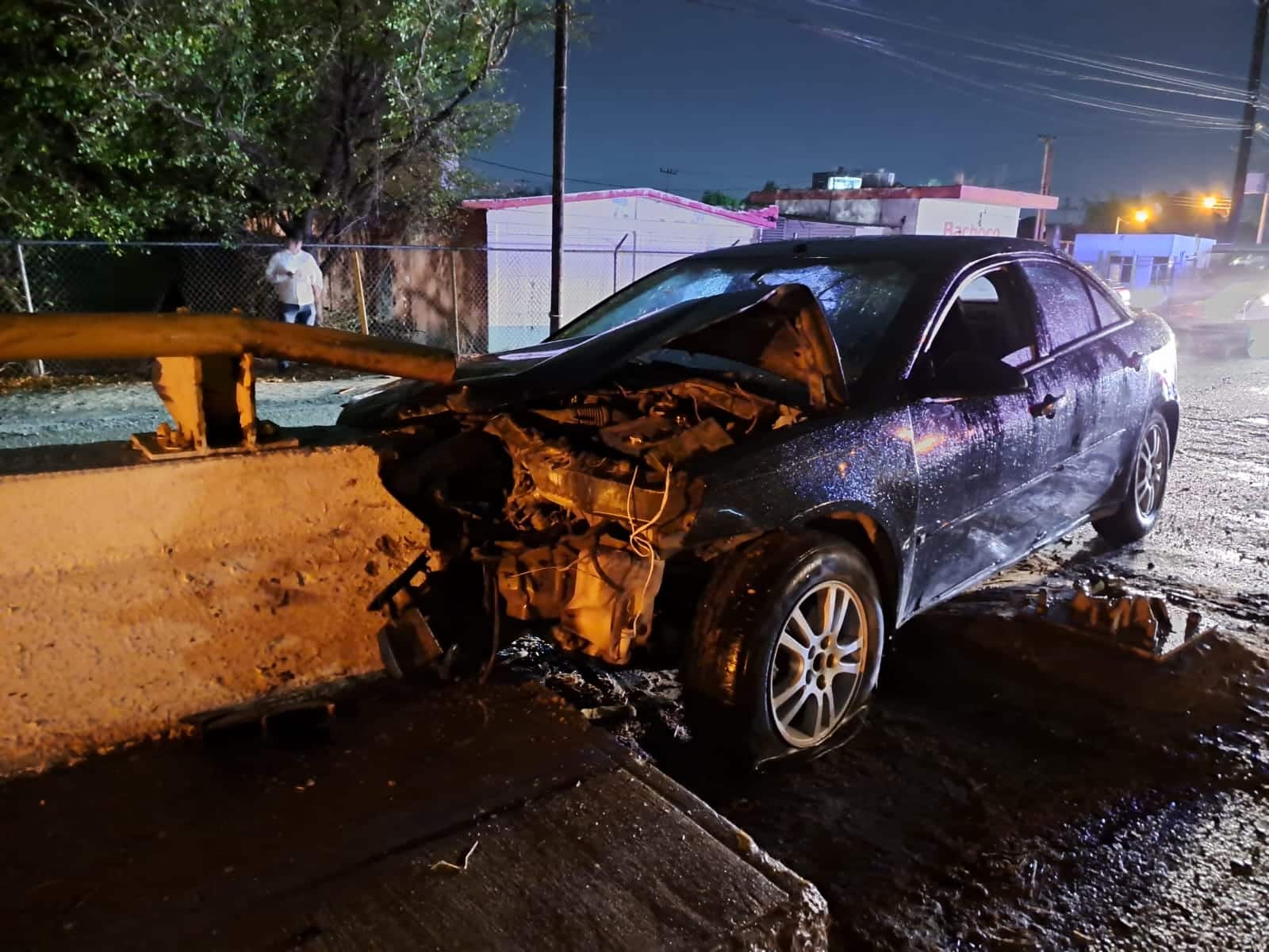 Auto destrozado de la parte delantera, impactado contra un muro de concreto