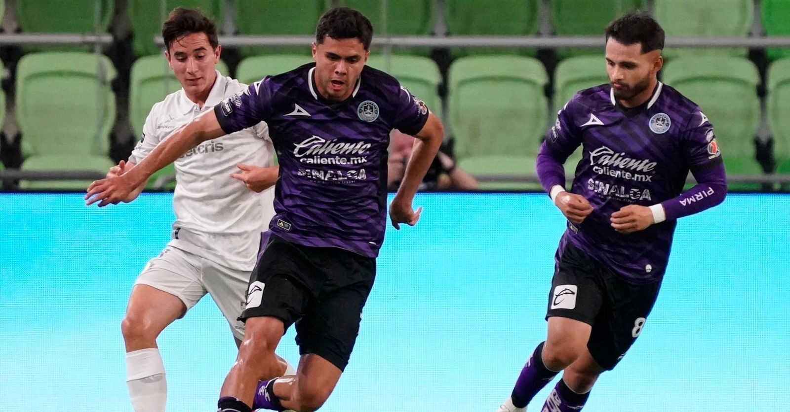 Dos jugadores de Mazatlán FC llevando la pelota y uno de FC Juárez va por detrás