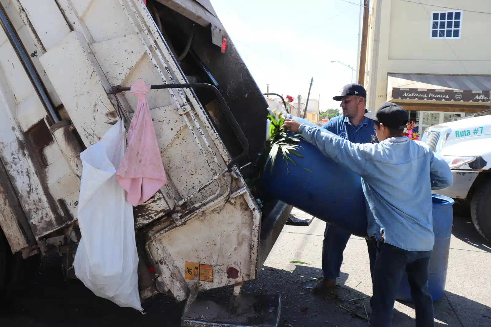 Trabajadores arrojando basura de un bote al camión recolector