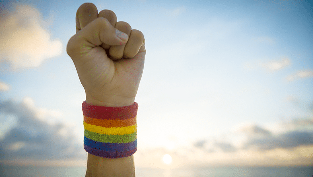 Puño levantado al cielo con una pulsera de arcoíris