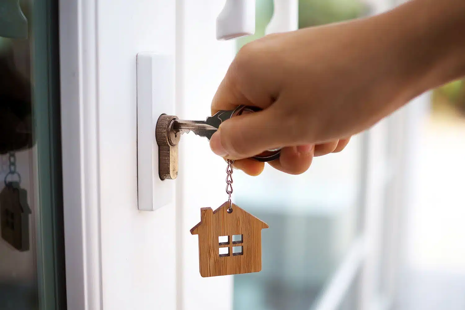 Alguien abriendo la puerta con una llave que tiene una casa de llavero