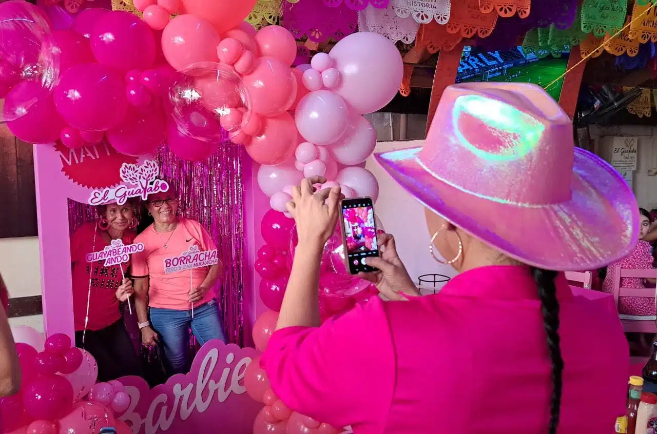 Asistentes tomándose fotografías en la caja de Barbie junto a una llamativa decoración rosada