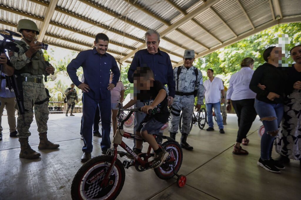 Gobernador y funcionarios entregando una bicicleta a un niño de San José de las Delicias