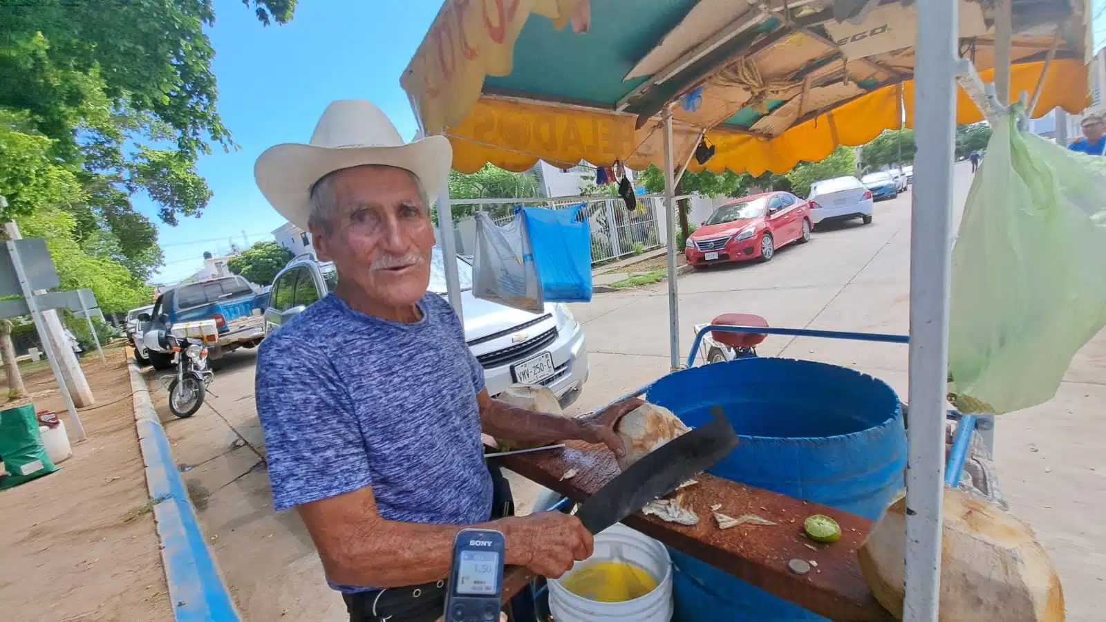 Don José Apodaca Gastélum pelando cocos en su triciclo
