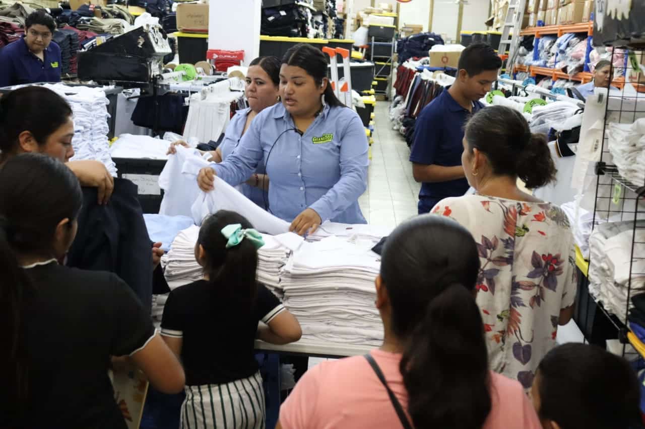 Padres y madres de familia acudiendo con sus hijos al canje de uniformes y útiles escolares