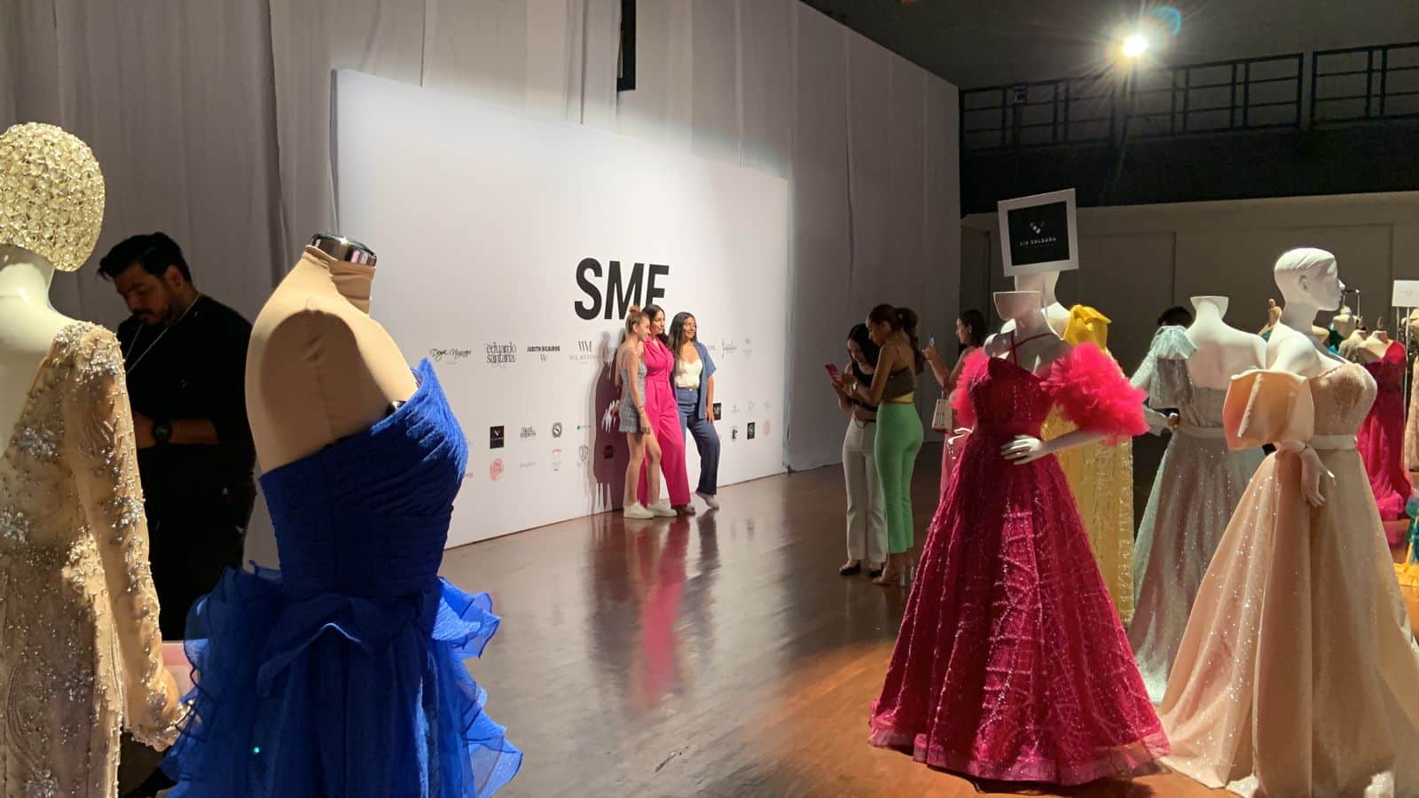 Modelos muestran sus atuendos mientras son fotografiadas entre maniquís con vestidos