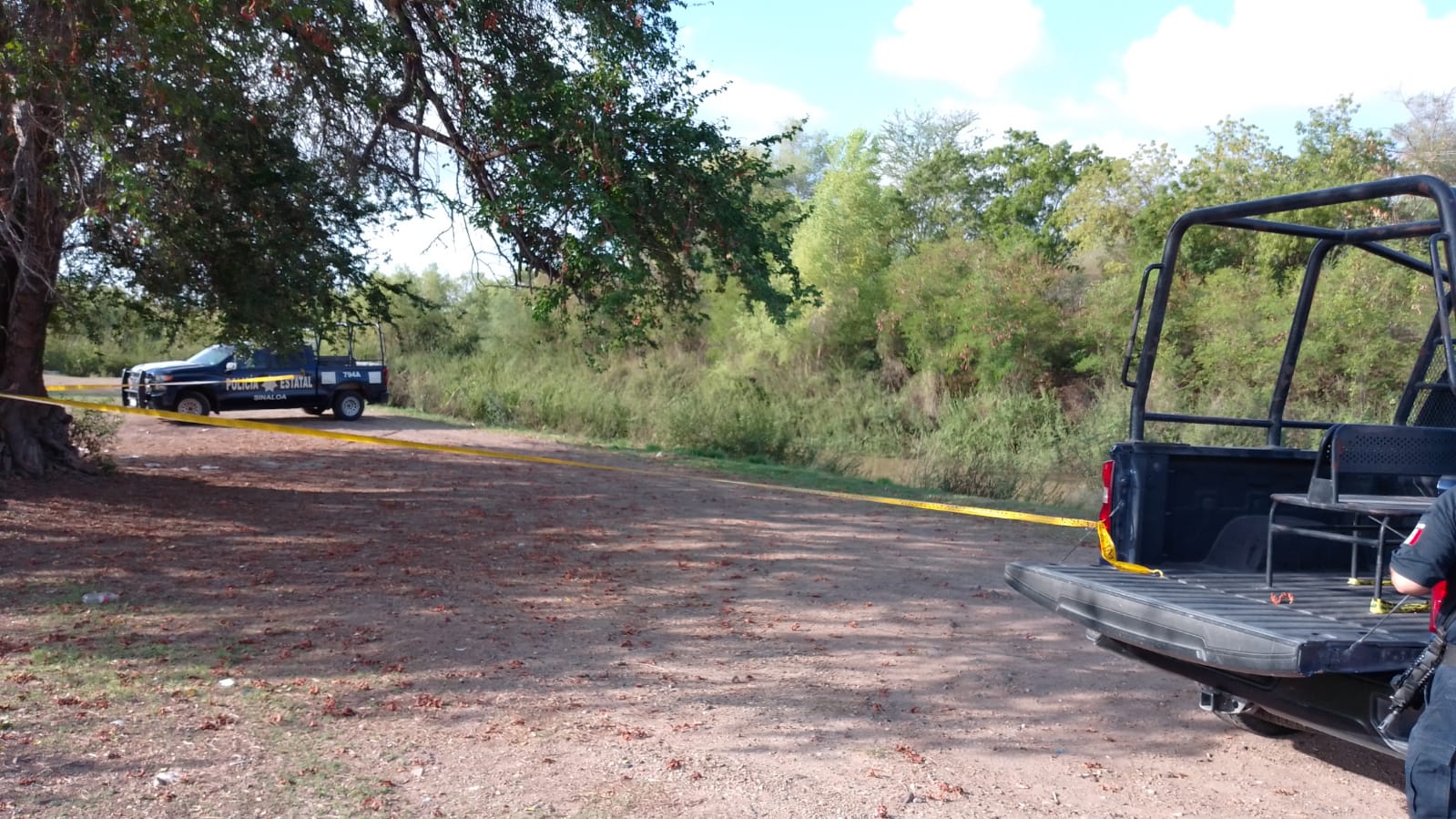 Zona de terracería acordonada junto a dos vehículos de la Policía Municipal